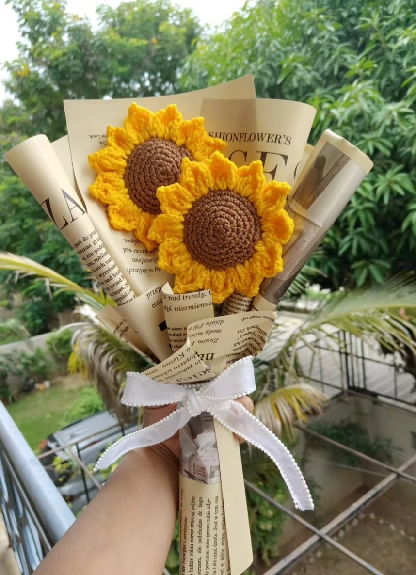 Crochet sunflower bouquet wrapped in newspaper print with a white ribbon